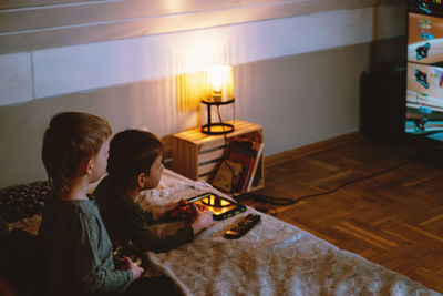 Kids playing video games at home on the bed at night. boys using game console and having fun in the