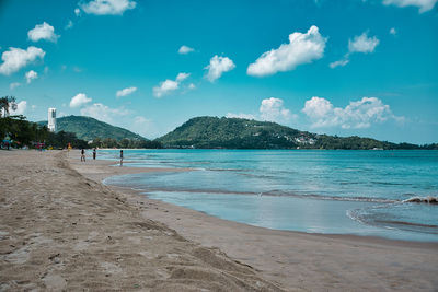 Empty, calm sandy patong beach in phuket with turquoise blue clear water and cirrus cloudy sky