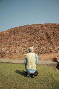 Rear view of man on field against clear sky