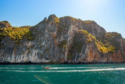 Scenic view of sea by mountain against sky