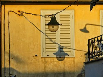 Low angle view of electric lamp hanging on wall