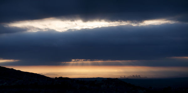 Silhouette of mountains against cloudy sky