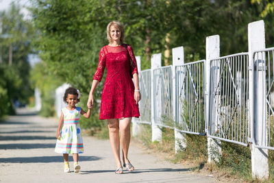 Full length of mother with daughter standing outdoors