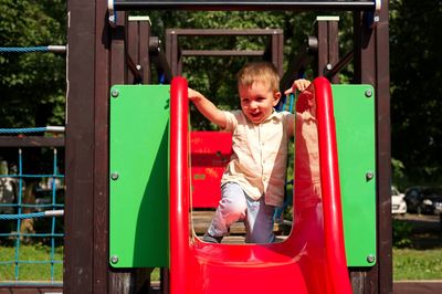 Little toddler playing on the playground and sitting on a slide