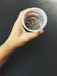 Cropped image of hand holding straight pin in disposable cup