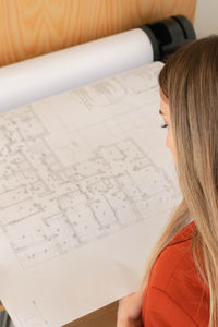 Close up top view of plotter printer printing in large format floor plans by young beautiful woman