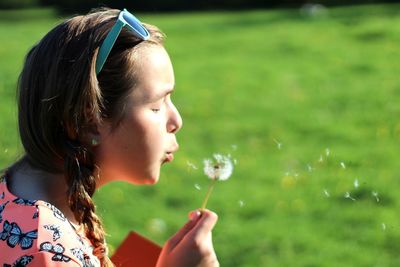 Side view of girl blowing dandelion