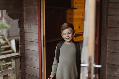 Portrait of smiling boy standing at doorway of house during vacation