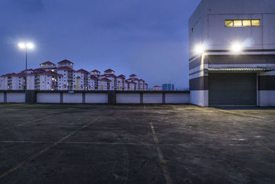 Illuminated building by street against sky at night