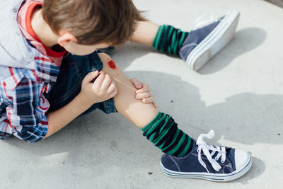 High angle view of boy with wound on knee at skateboard park