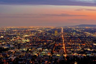 Illuminated cityscape against sky during sunset