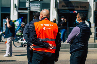 Rear view of people walking on street in city