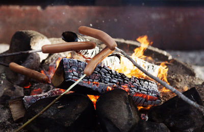 Grill sausages over an open fire outdoors