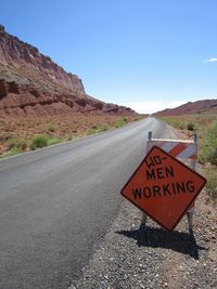 Road sign on rock against sky