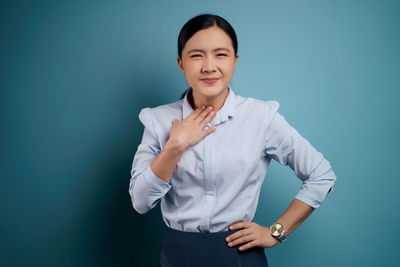 Portrait of a smiling young woman against blue background
