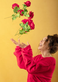 Woman holding pink flowers against wall