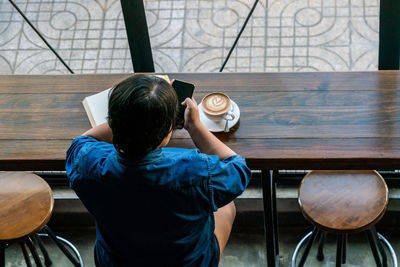 Rear view of man sitting on table