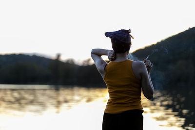 Rear view of man standing in lake against sky