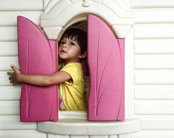 Cute girl opening window of playhouse