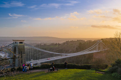 People on bridge against cloudy sky