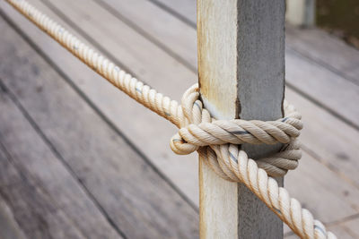 Fence pole tied with rope, rope knot on fence of wooden bridge