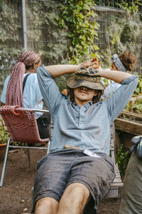 Young man with hands behind head resting in community garden