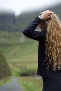 Woman with hand in hair standing outdoors