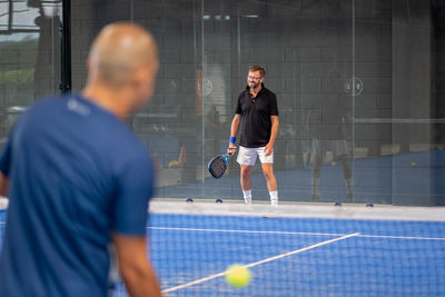 Monitor teaching padel class to man, his student - trainer teaches boy how to play padel 