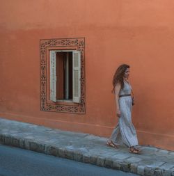 Full length of woman walking against building