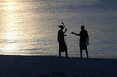 Silhouette men standing at beach during sunset