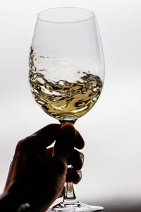 Close-up of hand holding wineglass against white background
