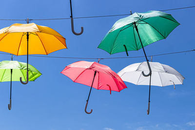 Low angle view of umbrellas against blue sky