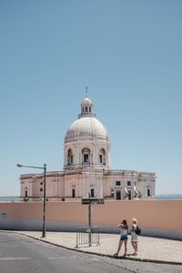 Women standing sidewalk by national pantheon against sky