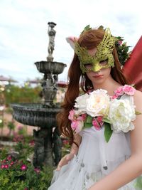 Portrait of mid adult woman wearing mask while standing at park against clear sky