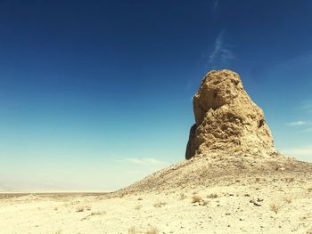 Low angle view of rock formations in desert against blue sky