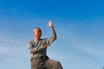 Man gesturing while standing against sky