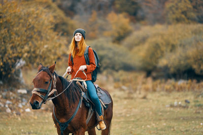 Close-up of young woman riding horse on field