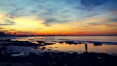 Scenic view of sea against dramatic sky during sunset