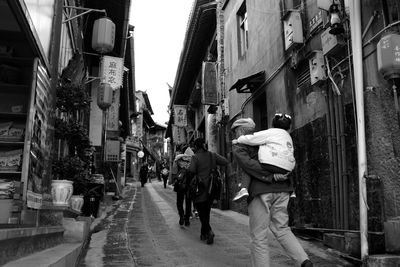 People walking on footpath by buildings in city