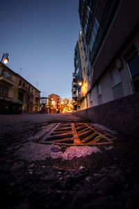 Surface level of road amidst buildings against sky at night