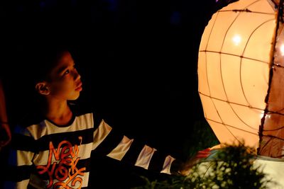 Boy looking at illuminated lantern during night