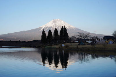 Scenic view of lake and mountains against clear blue sky