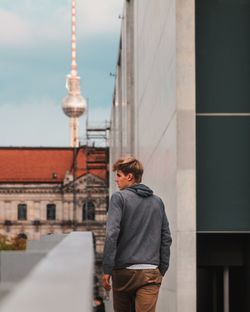 Rear view of man walking against building