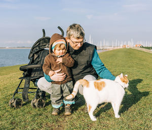 Full length of grandfather and daughter with cat on grass