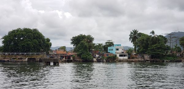 Scenic view of river by buildings against sky