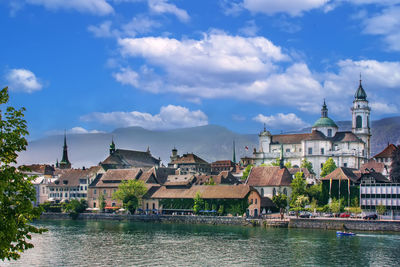 Buildings by river against sky