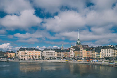 City at waterfront against cloudy sky