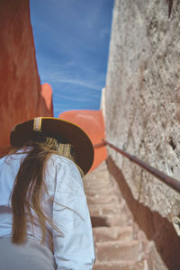 Rear view of young woman standing against sky