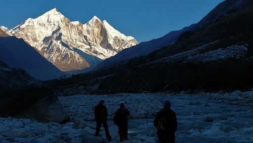 Rear view of people walking on snowcapped mountain