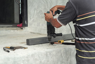 Selective focus on the hands of worker hold the drilling machine during drilling on the cement floor 